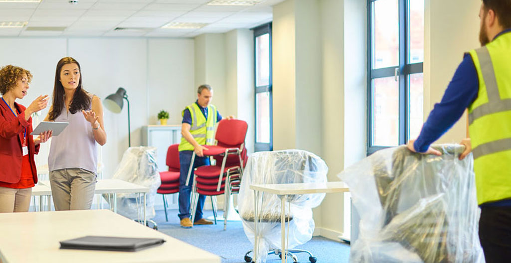 Déménageurs professionnels portant soigneusement du mobilier de bureau dans un couloir de locaux professionnels